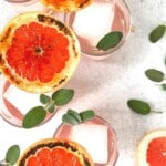 Overhead view of a grapefruit gin cocktail in a glass with bruleed grapefruit garnish.