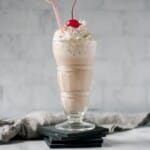 Nutella milkshake in a glass with whipped cream and a cherry