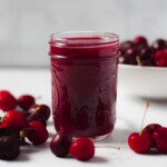 Cherry compote in mason jar with cherries on side.