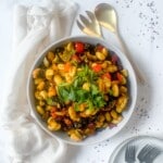 Oven baked gnocchi with sausage and vegetables in a bakng dish with a serving fork and spoon.