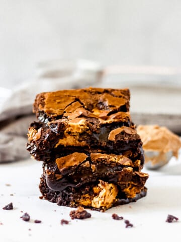 Stack of biscoff brownies with scoop of cookie butter in background.