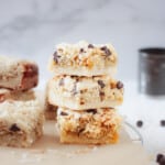 Chocolate coconut bars stacked with chocolate chips scattered around.