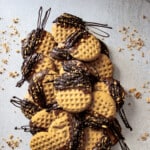 Overhead shot of chocolate dipped peanut butter cookies stacked with sprinkles of chopped peanuts around the cookies.