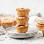 Stack of raspberry and white chocolate muffins on a plate with other muffins in the background.